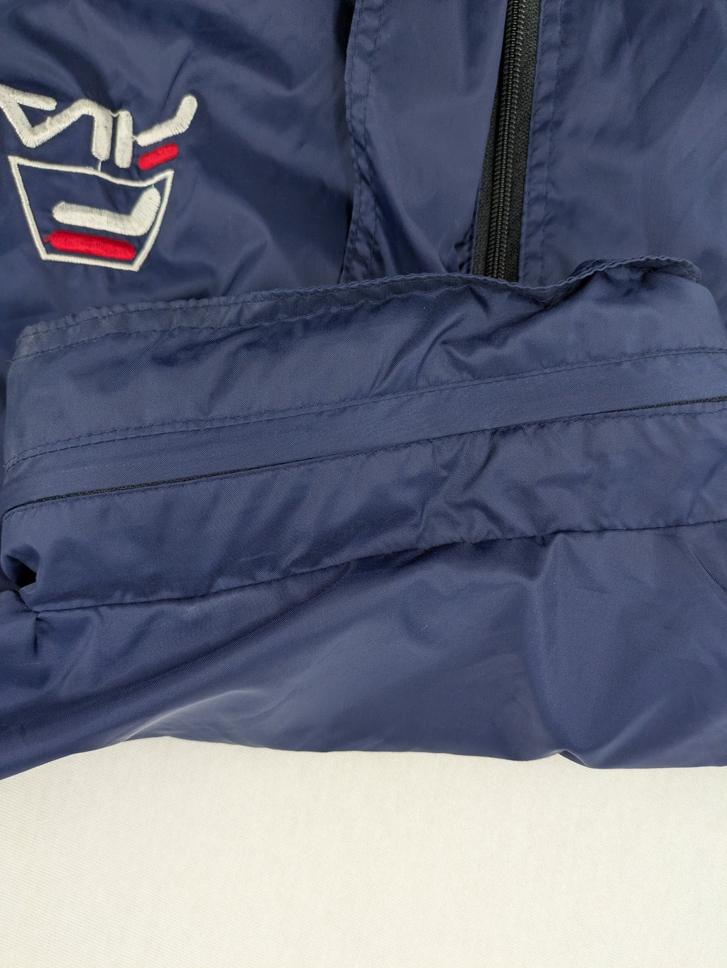 Fila navy windbreaker jacket with large embroidered logo on chest and back.