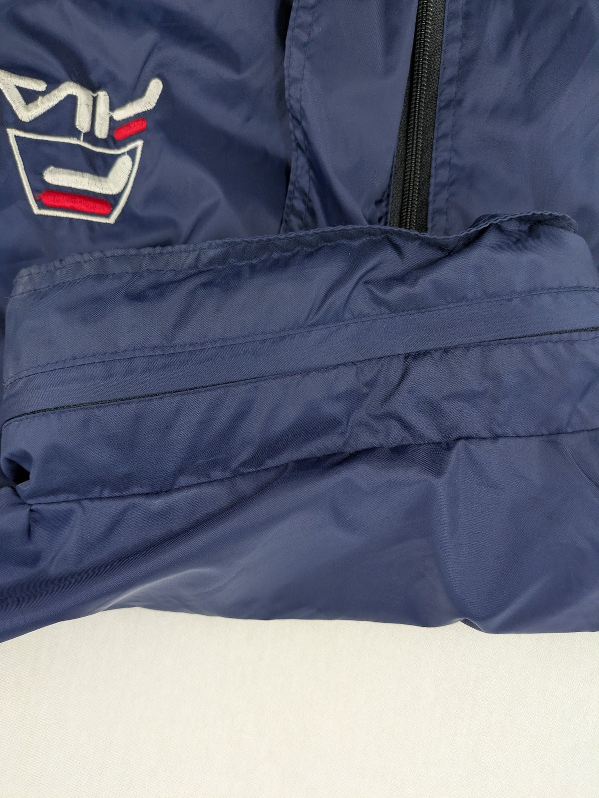 Fila navy windbreaker jacket with large embroidered logo on chest and back.