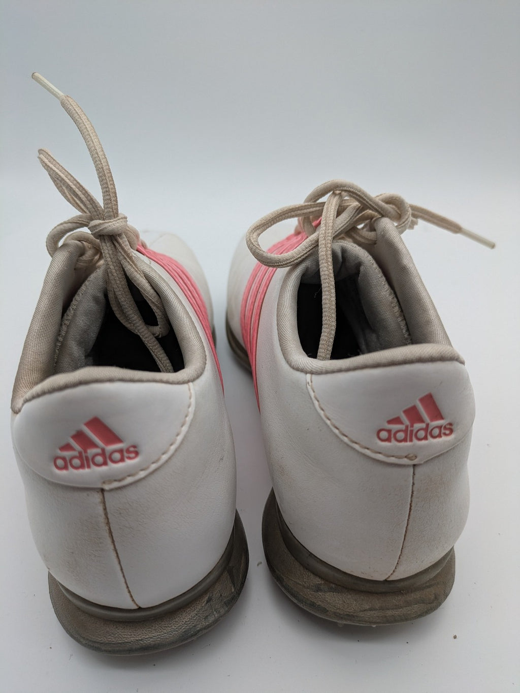 Adidas white golf shoes with pink stripes, Thintech and TRAXION technology, stylish design.
