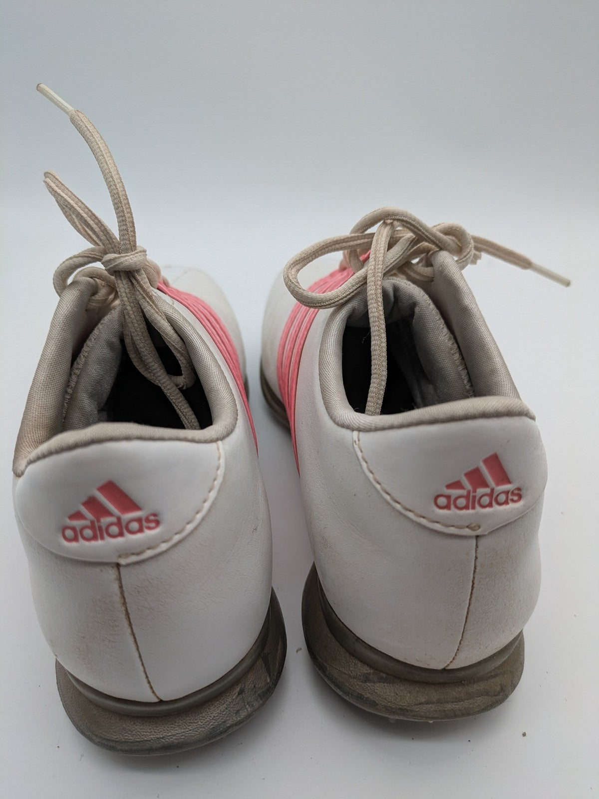 Adidas white golf shoes with pink stripes, Thintech and TRAXION technology, stylish design.