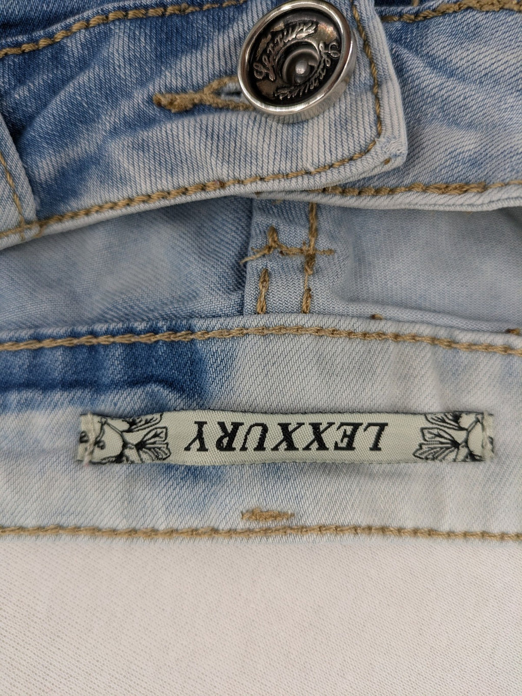Lexxury blue skinny jeans distressed with knee rips and light wash finish.