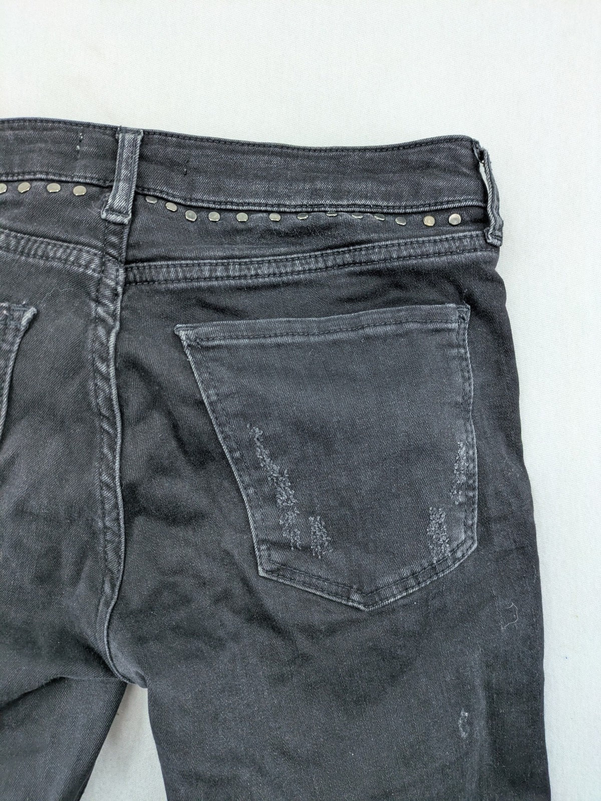 Zara Woman black skinny jeans with distressed details, silver studs, and frayed hem.