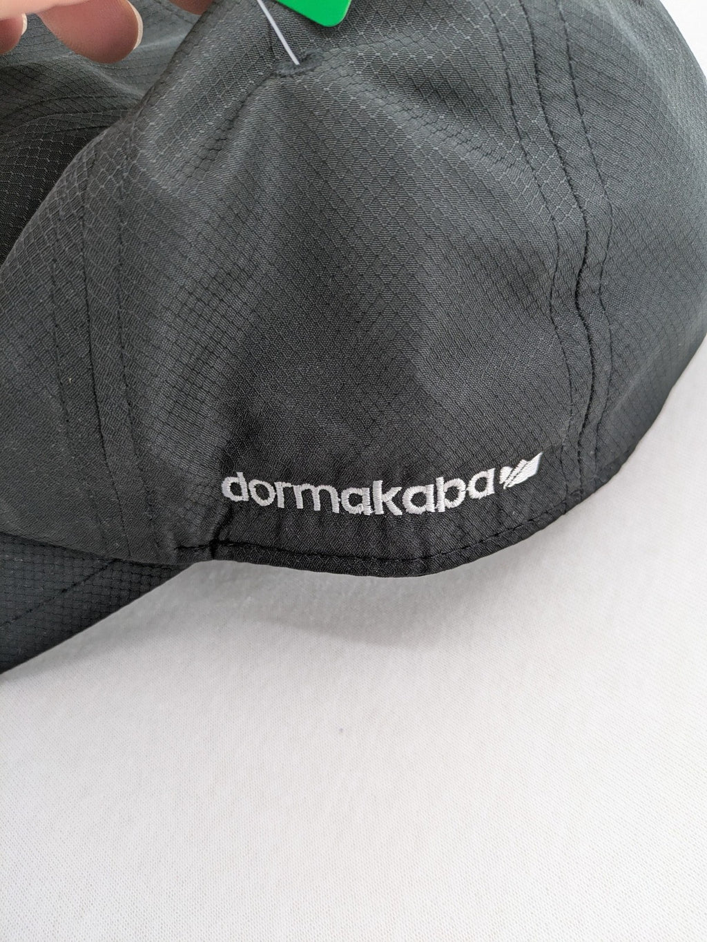 Funktional grey baseball cap with embroidered Dormakaba logo and modern ripstop texture.