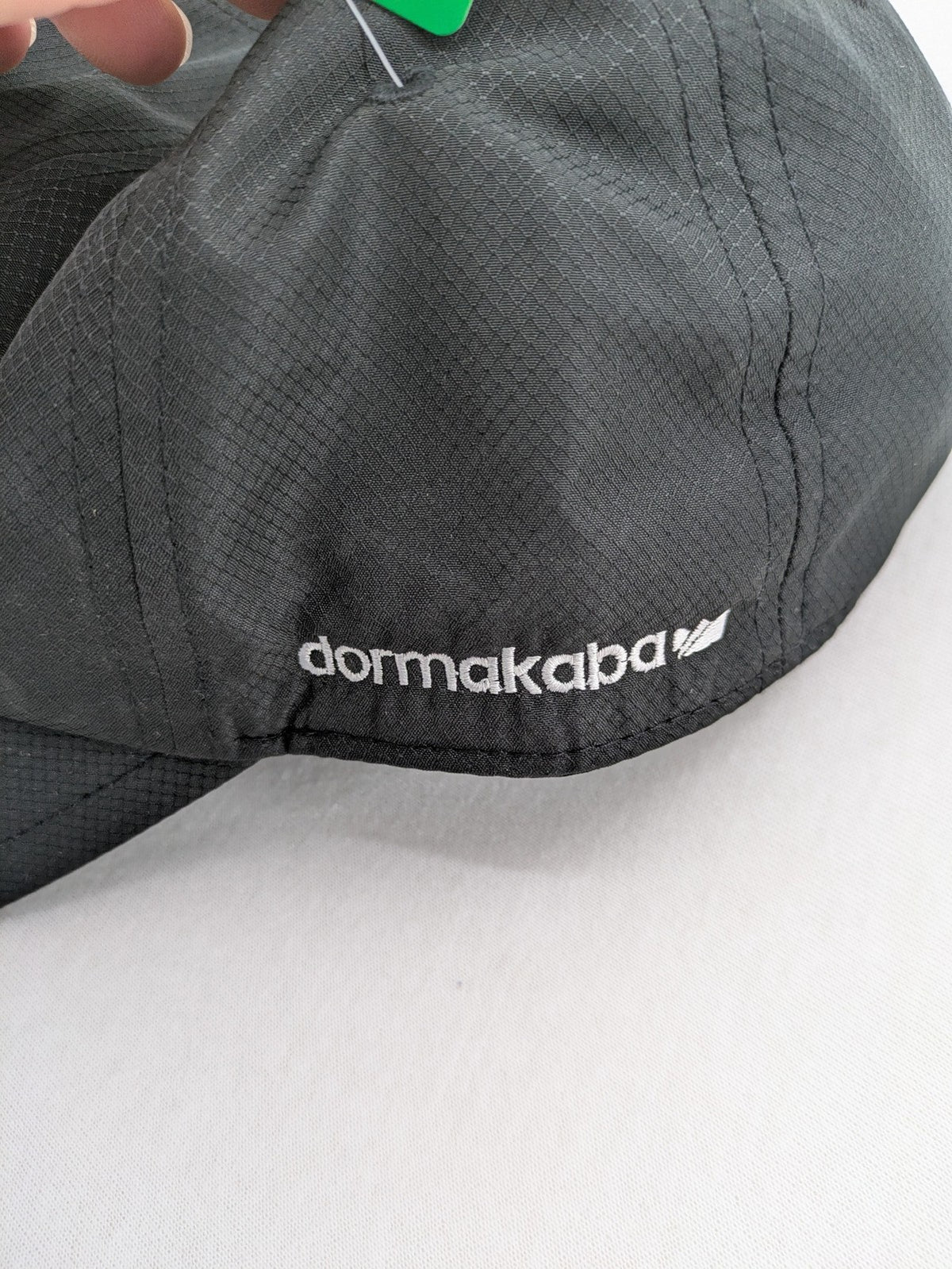 Funktional grey baseball cap with embroidered Dormakaba logo and modern ripstop texture.