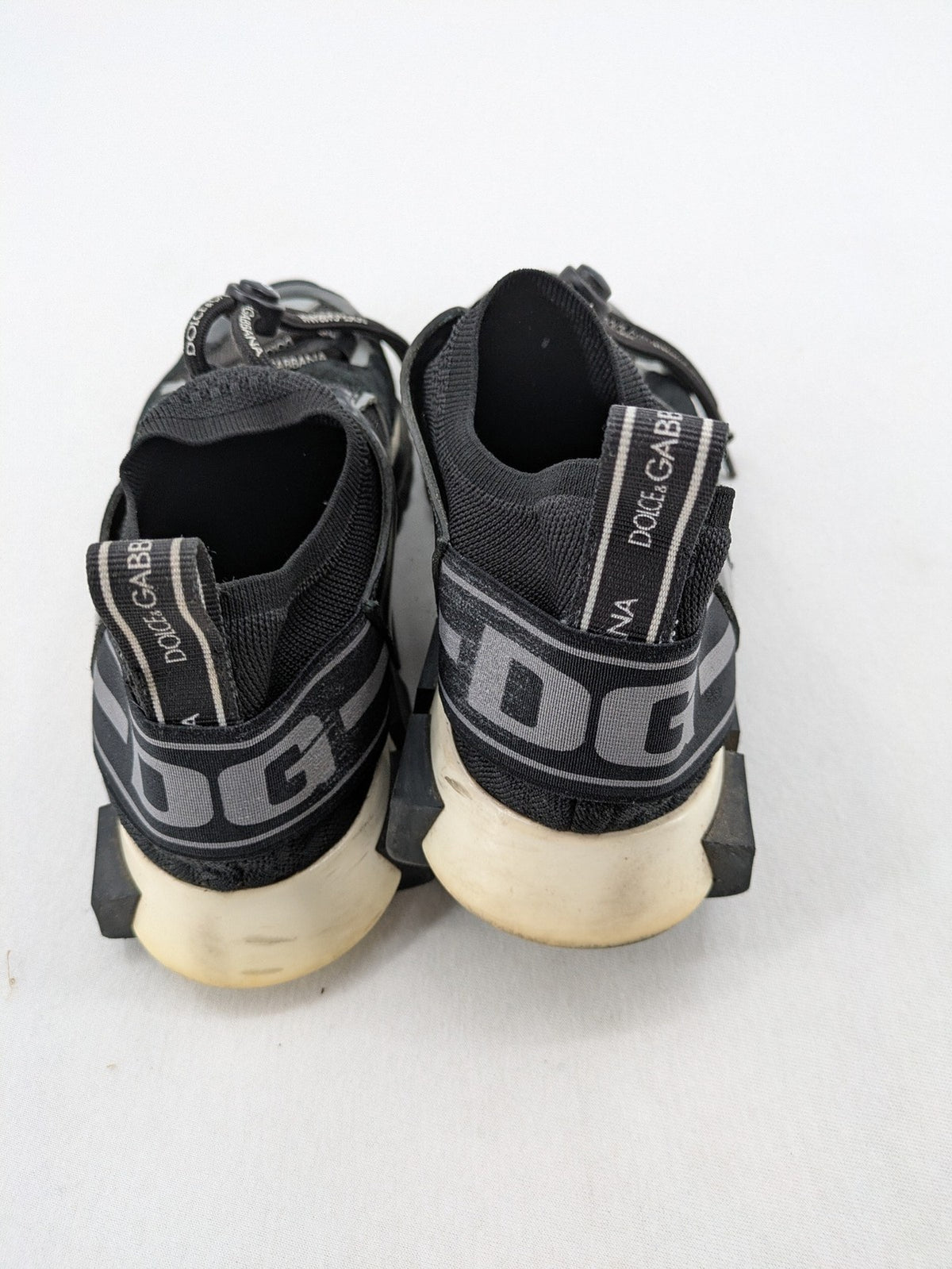 Dolce & Gabbana black sneakers with logo laces and segmented sole design.