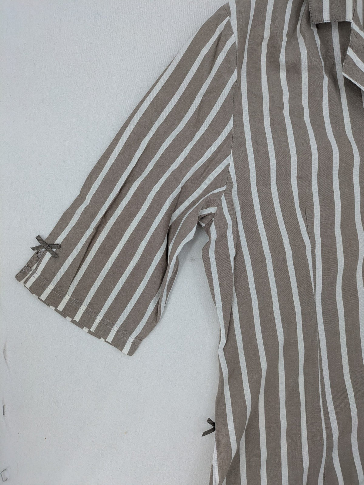 Body Sunday beige and white striped loungewear top with bow accents and button placket.