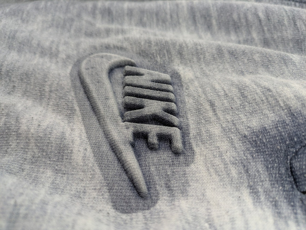 Nike grey acid wash jogger shorts with embossed logo and zip pockets.