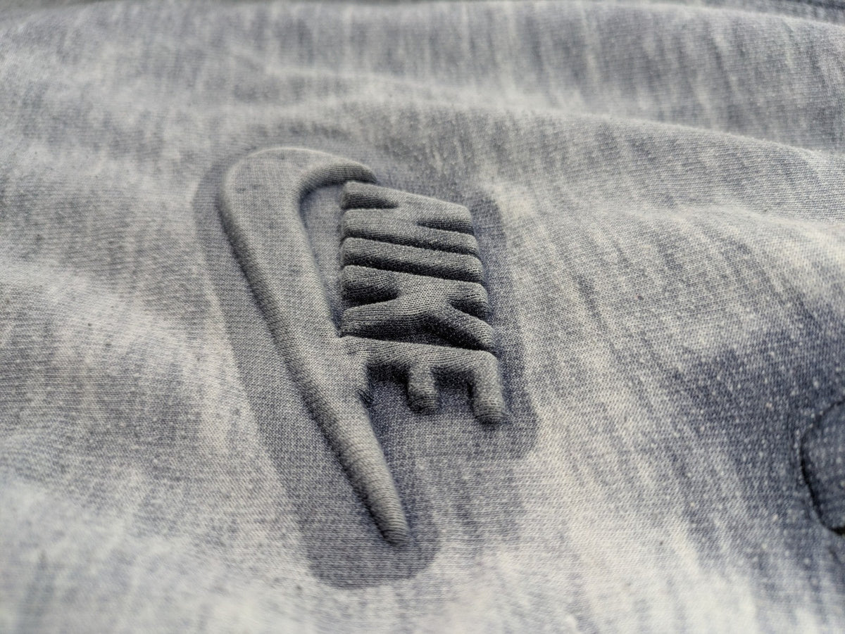 Nike grey acid wash jogger shorts with embossed logo and zip pockets.