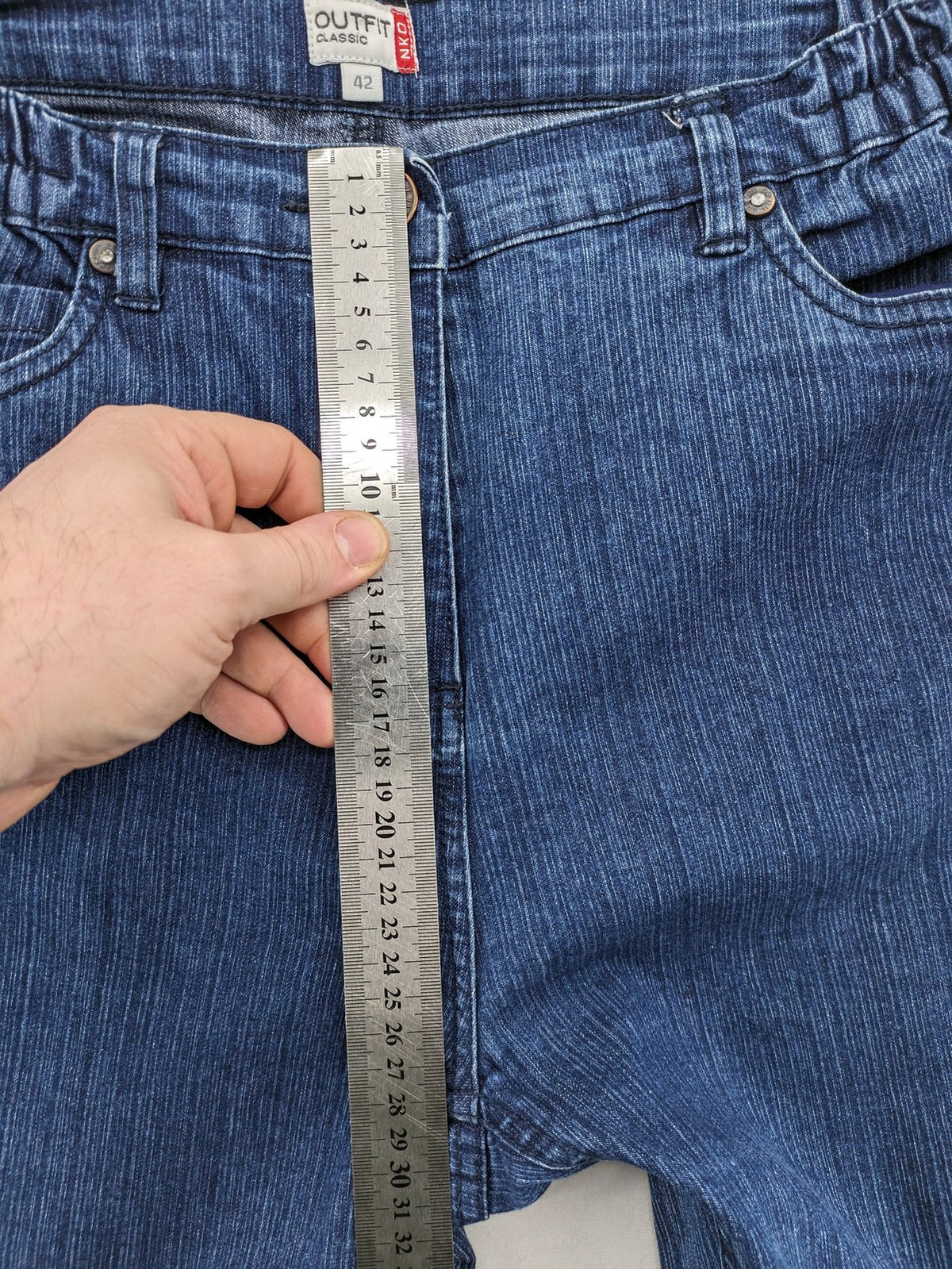 Outfit blue straight jeans with elastic waistband and embroidered crown-wing emblem on pockets.