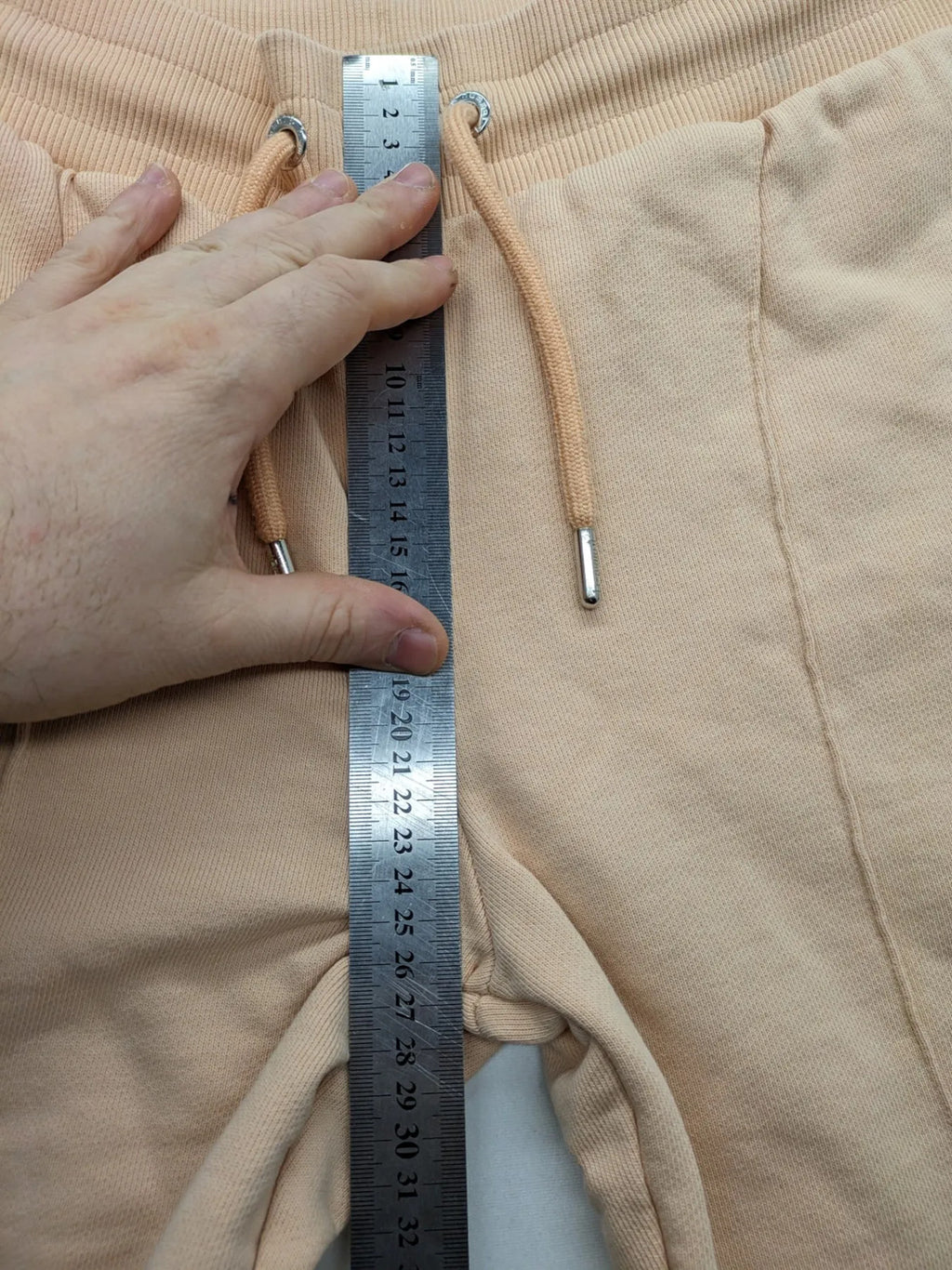 Hummel beige jogging pants with adjustable drawstring, embroidered logo, and ankle cuffs.