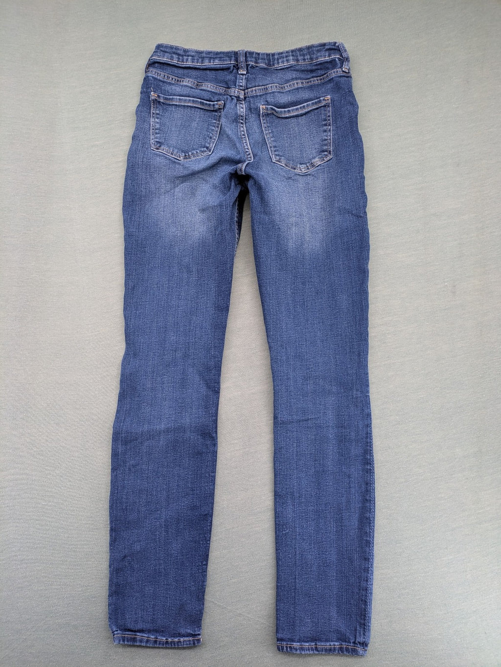 H&M blue skinny jeans with distressed knee details and classic 5-pocket design.