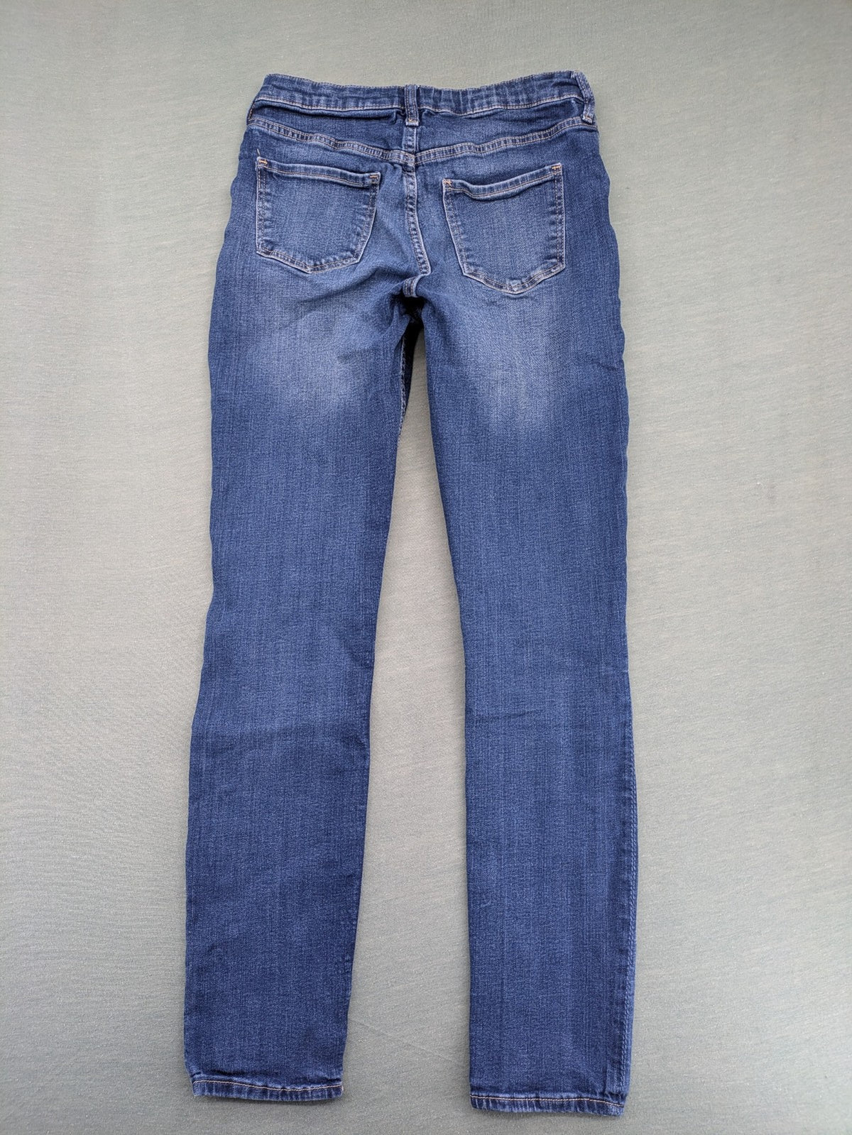 H&M blue skinny jeans with distressed knee details and classic 5-pocket design.