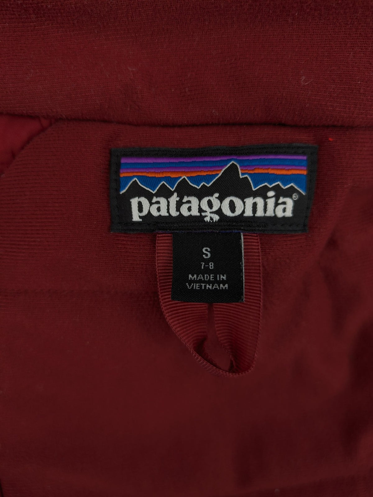 Patagonia red winter coat with hood, zip closure, snow skirt, and ski pass pocket.