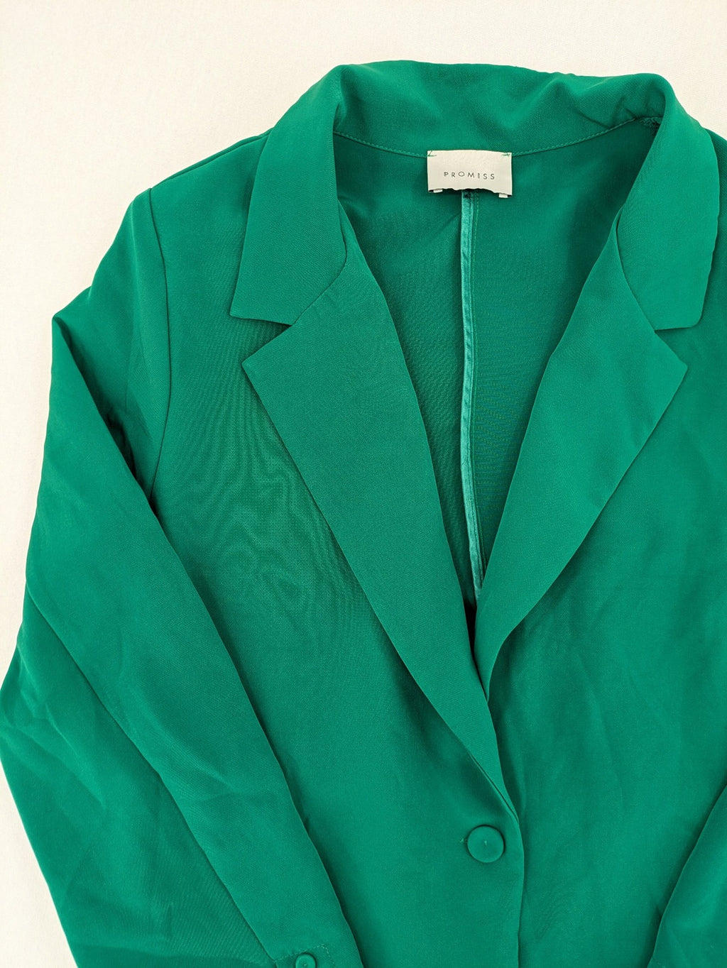 Promiss green blazer jacket single-button design with notch lapels and decorative pockets.