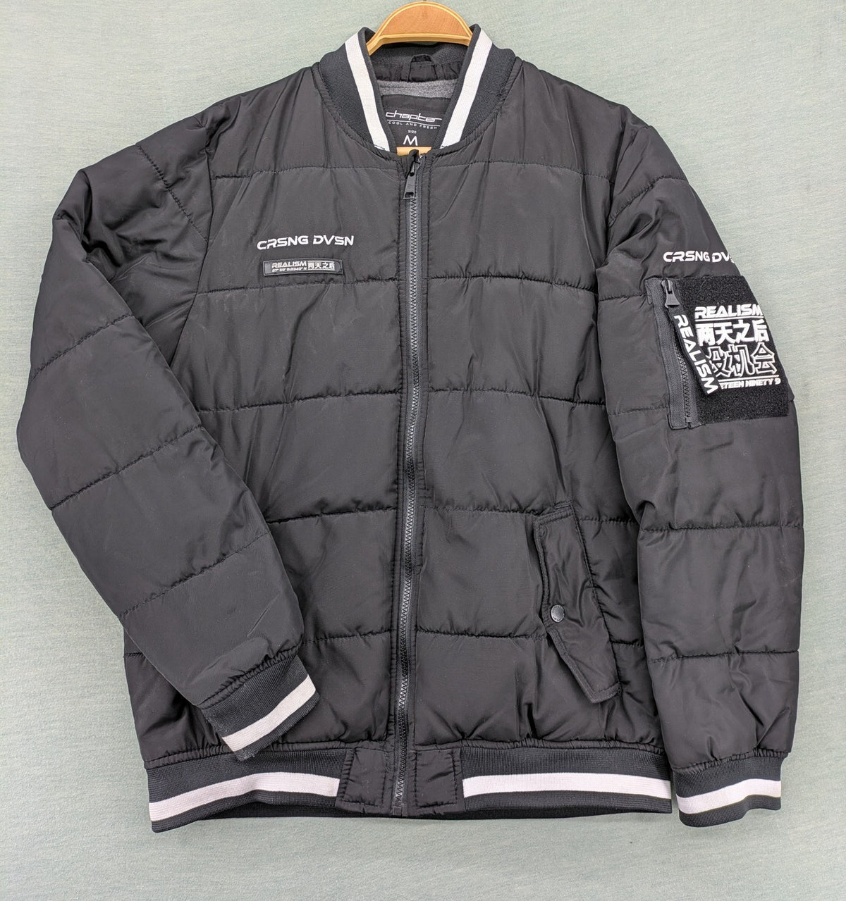 Chapter black bomber jacket with patches, striped ribbed cuffs, and full zip closure.