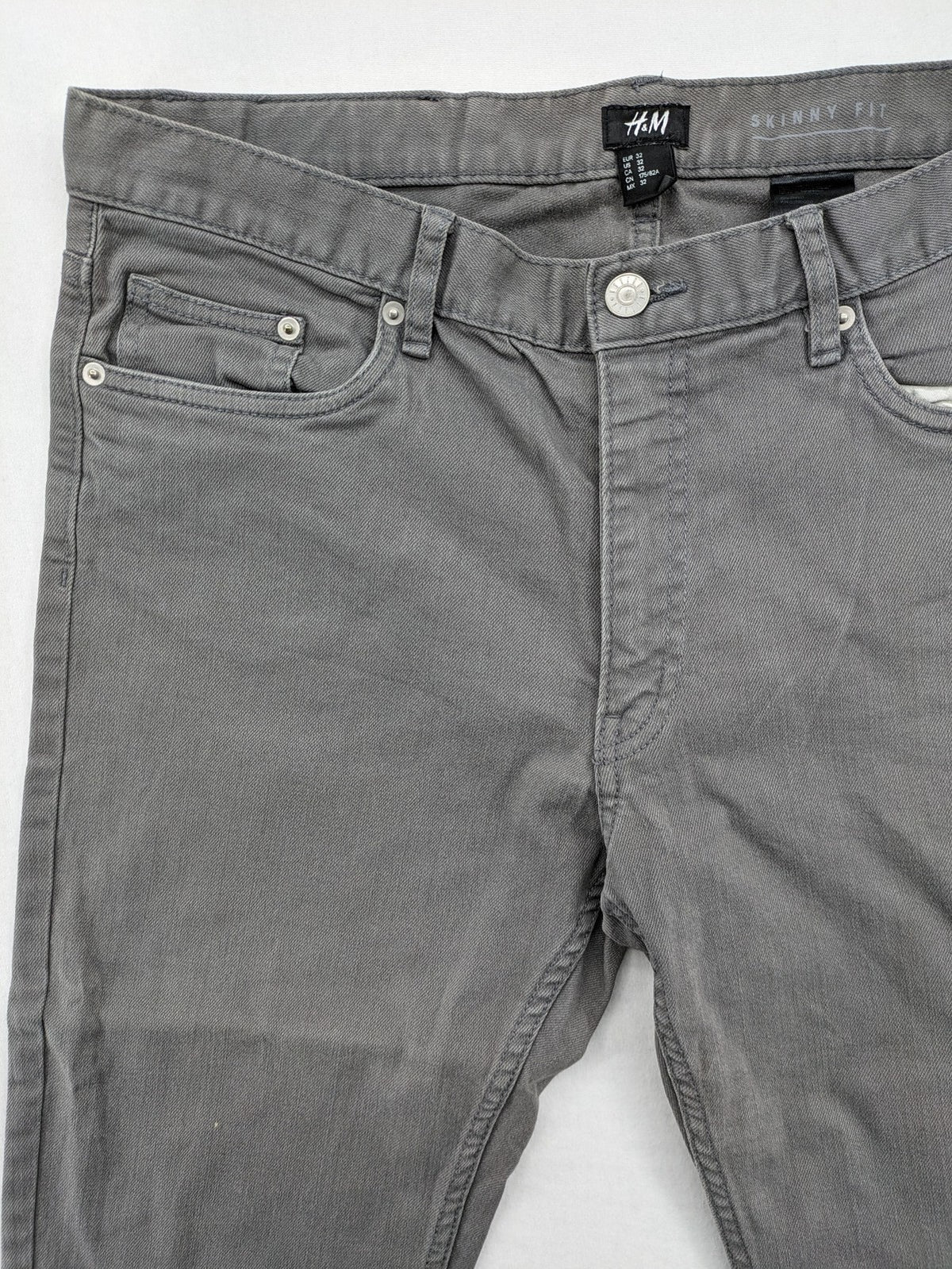 H&M grey skinny fit jeans with button closure and five-pocket design, cotton-elastane blend.