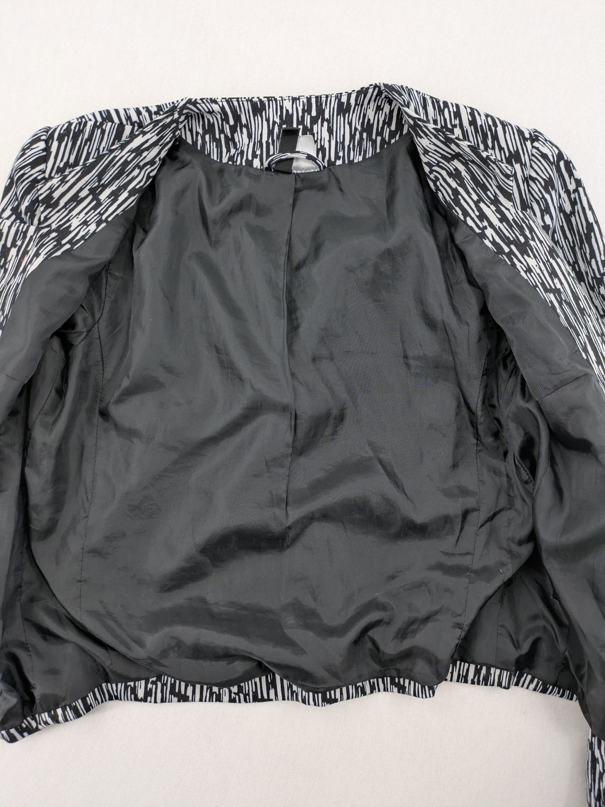 H&M Divided black and white patterned blazer with open front and two front pockets.