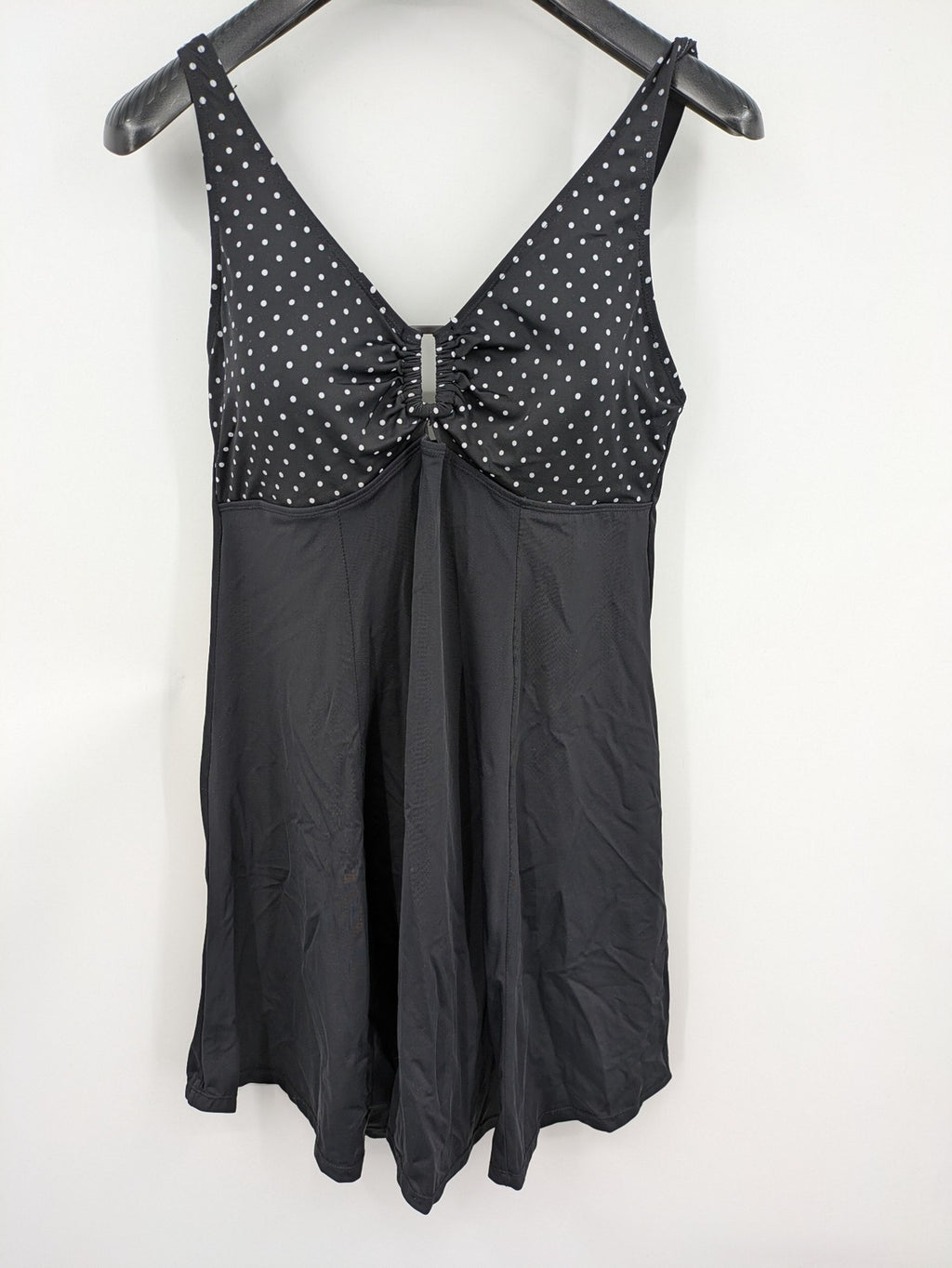 Elegante black swimsuit with white polka dots, V-neck, adjustable straps, and padded cups.