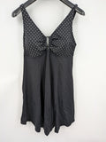 Elegante black swimsuit with white polka dots, V-neck, adjustable straps, and padded cups.