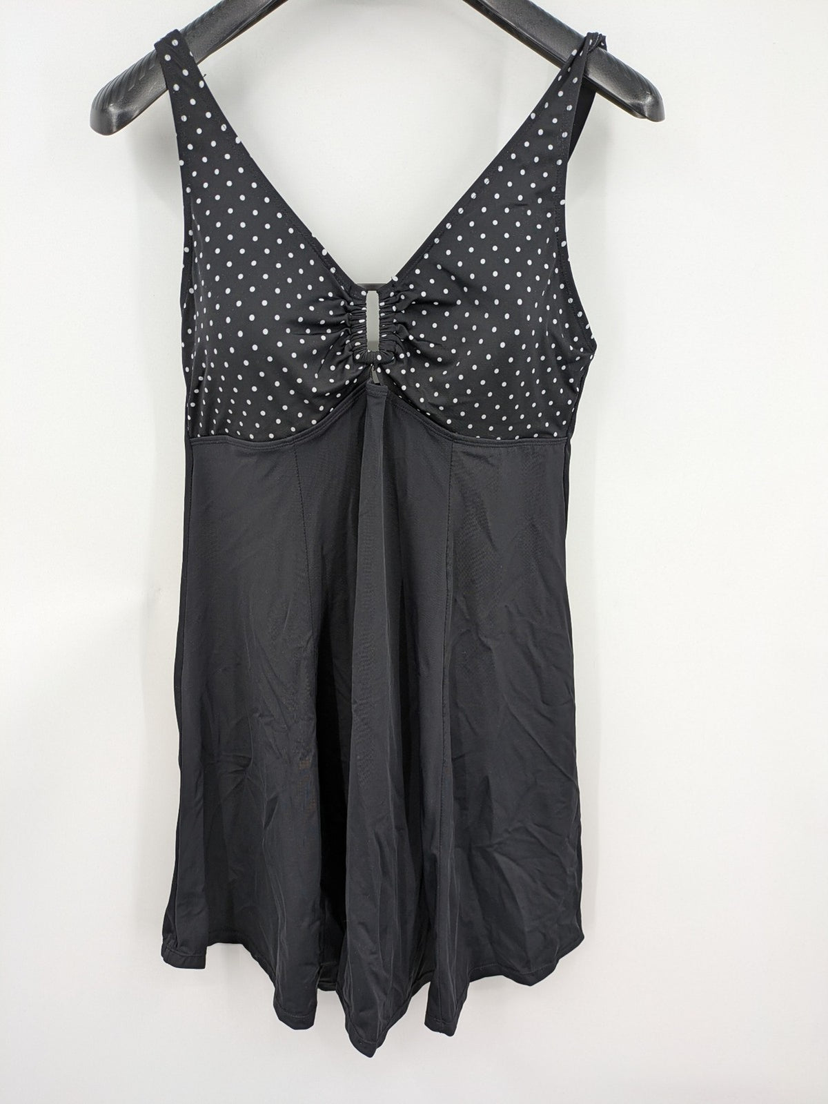 Elegante black swimsuit with white polka dots, V-neck, adjustable straps, and padded cups.
