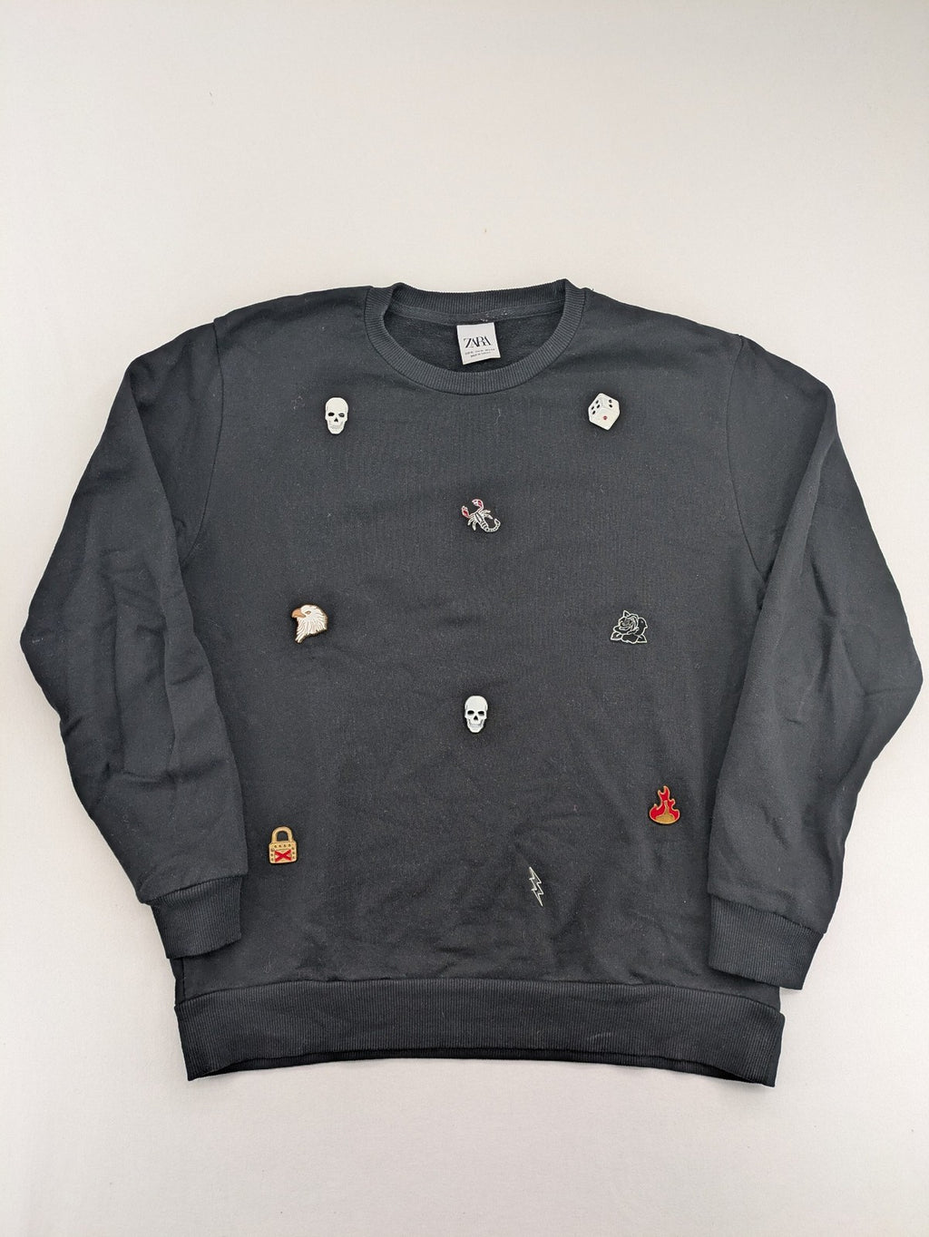 Zara grey turtle neck jumper with skull, scorpion, flame, and eagle embellishments.