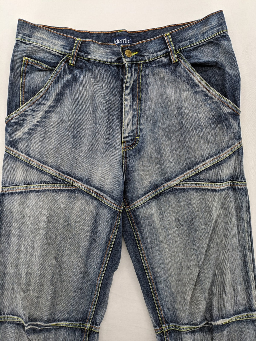 Identic orange straight jeans with paneled design and contrasting yellow stitching.
