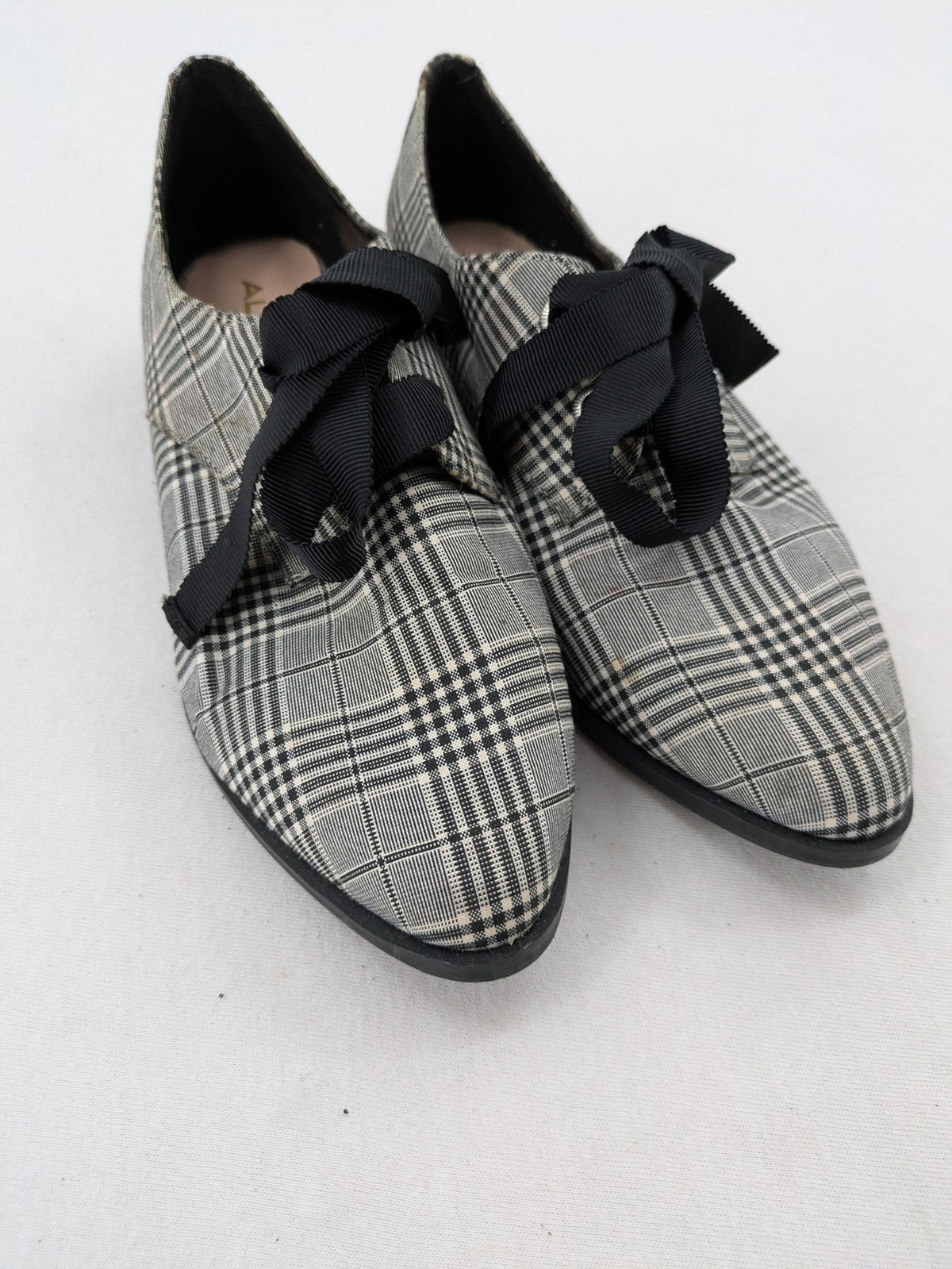 ALDO black and white checkered loafers with decorative bow detail and pointed toe.