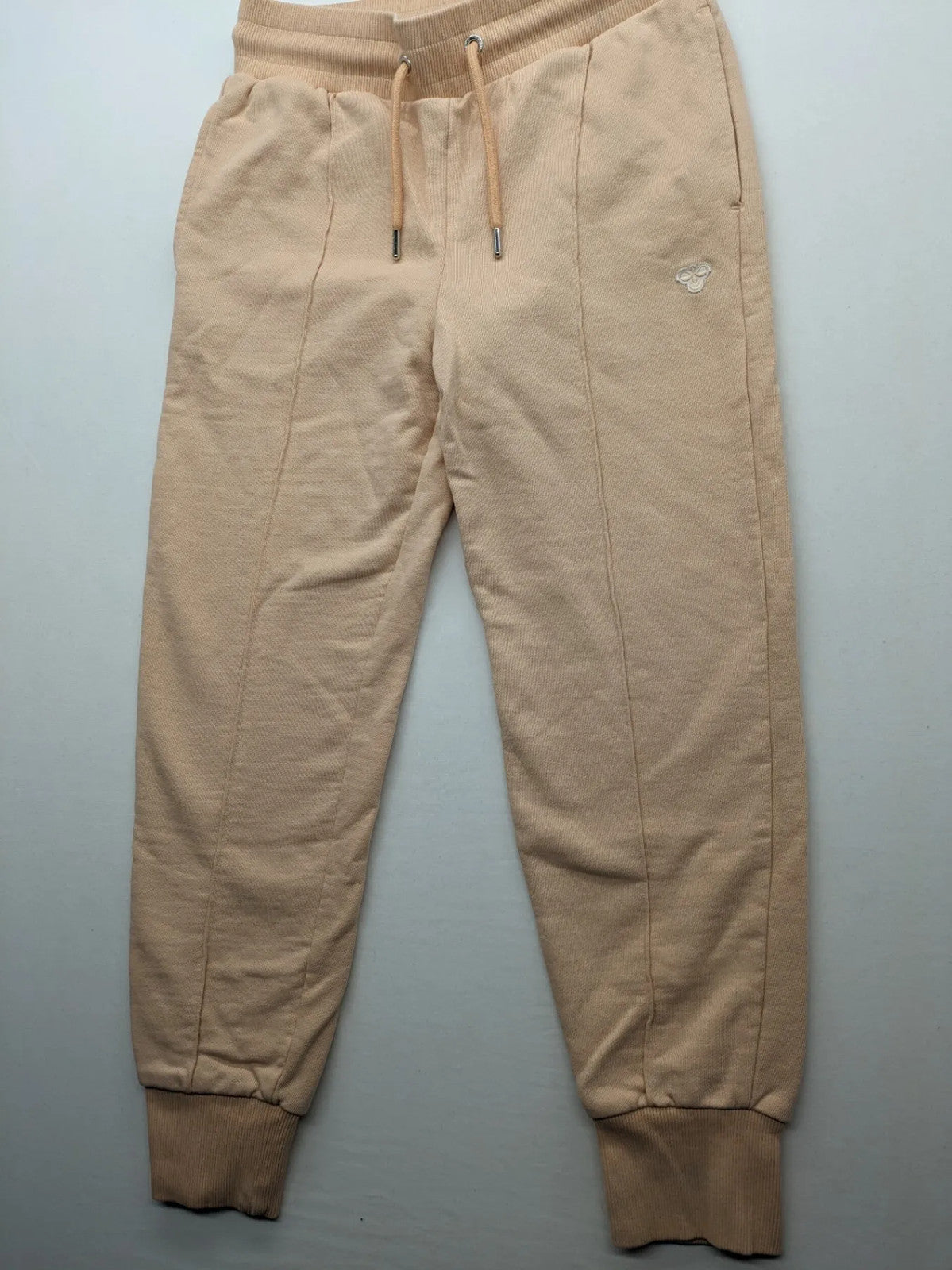 Hummel beige jogging pants with adjustable drawstring, embroidered logo, and ankle cuffs.