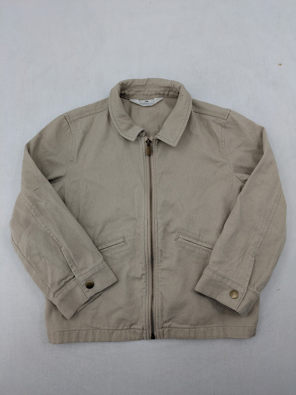 H&M beige twill coat with full zip, classic collar, and practical pockets.