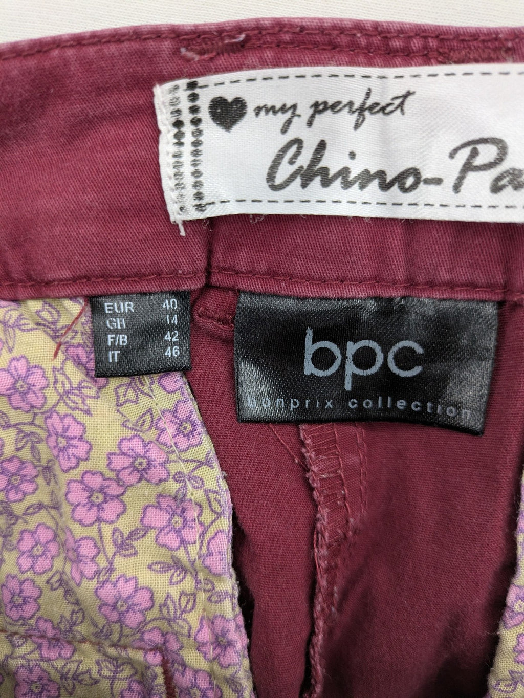 BPC Bonprix burgundy chino pants with front pleats and floral pocket lining.