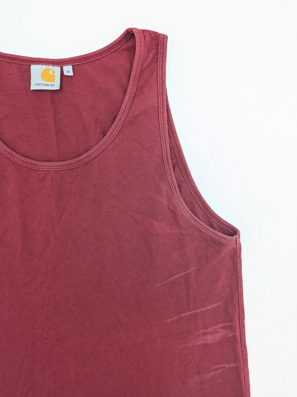 Carhartt burgundy tank top 100% cotton with iconic logo patch at hem.
