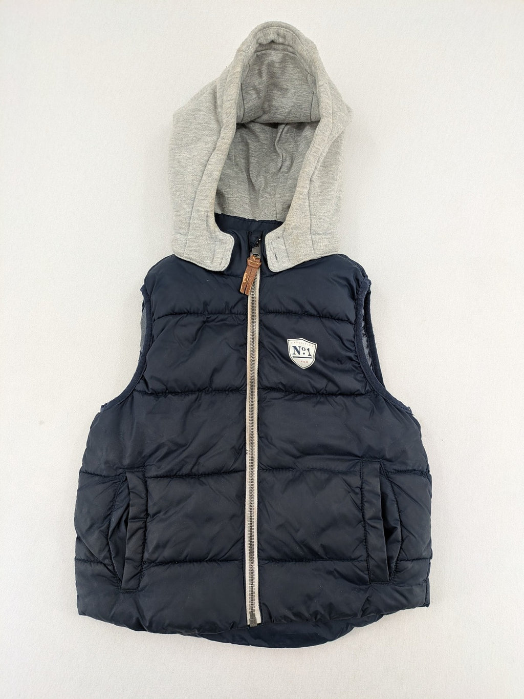 H&M navy puffer vest with grey hood and zip pockets for kids.