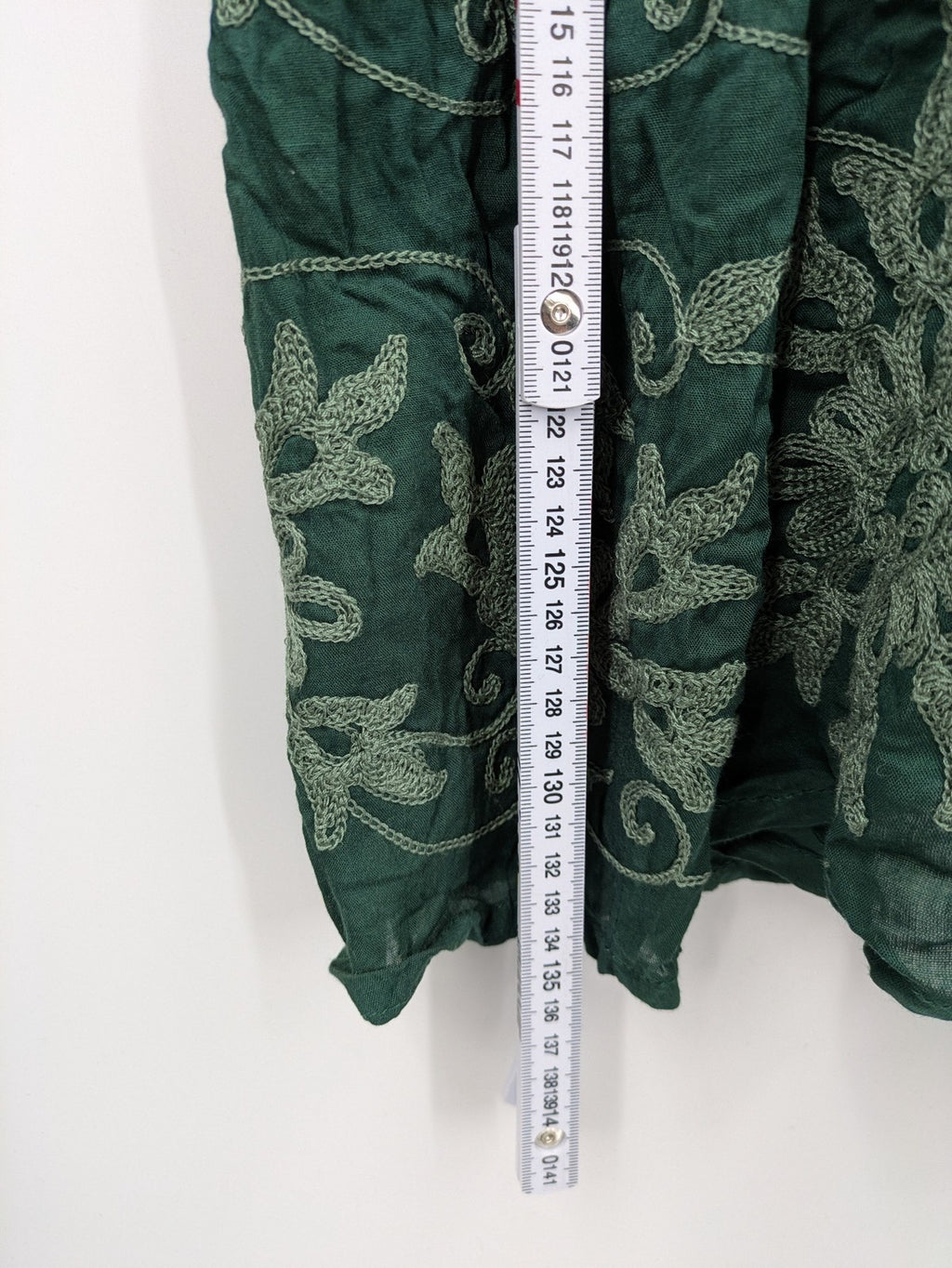 Boho green maxi dress with floral embroidery along tiered hem and adjustable spaghetti straps.