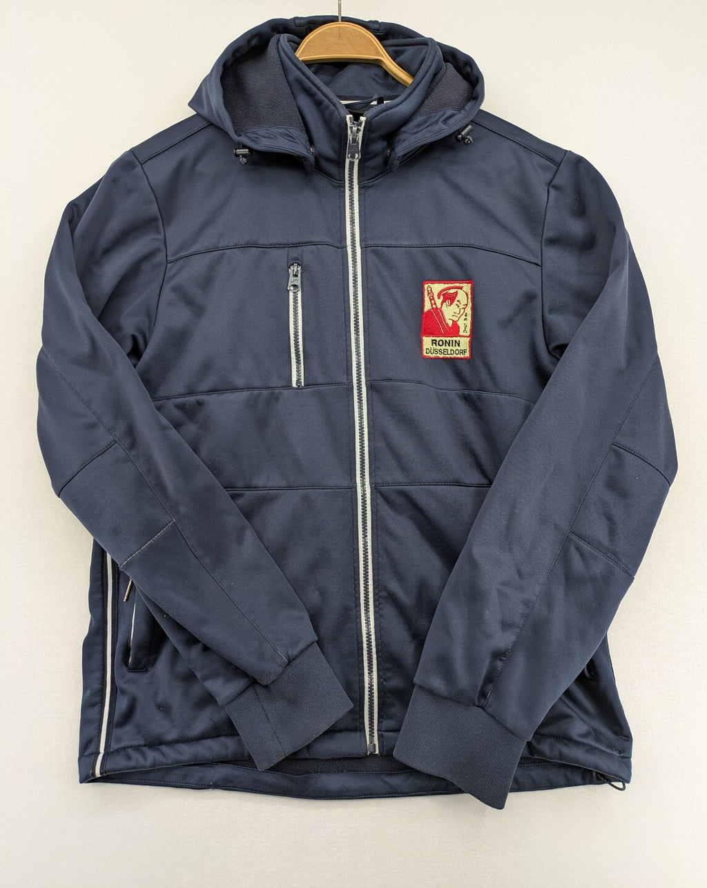 James & Nicholson beige softshell jacket with fleece lining and embroidered Ronin Düsseldorf patch.