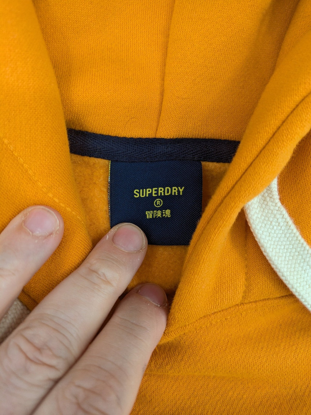 Superdry orange turtle neck jumper with textured logo patch and number 7 detail.