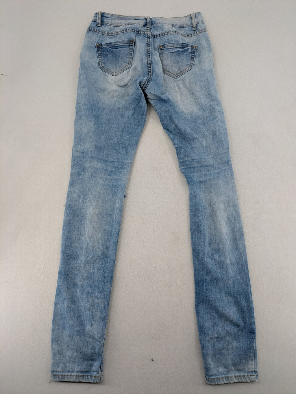 Lexxury blue skinny jeans distressed with knee rips and light wash finish.