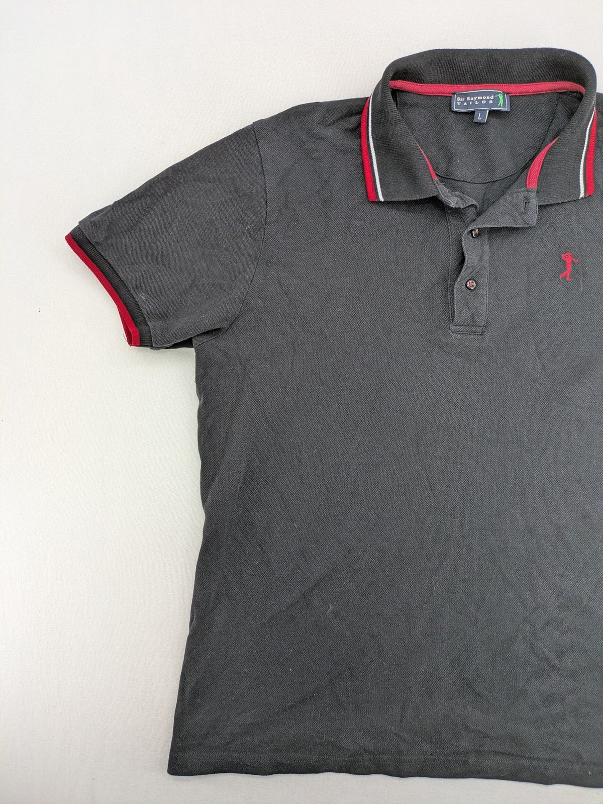 Sir Raymond Tailor black polo shirt with red and white striped collar, embroidered golfer logo.