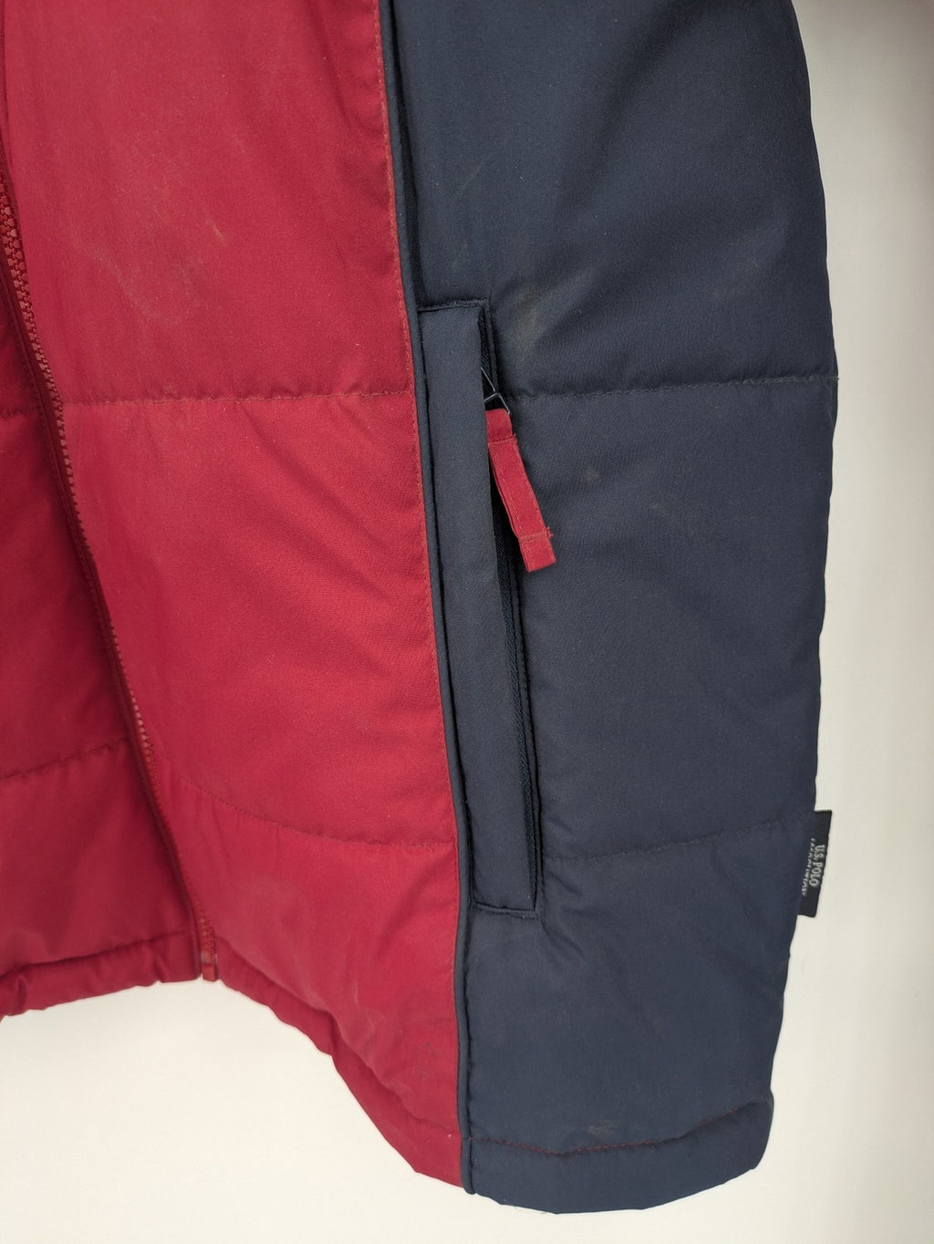 US Polo Assn. puffer jacket navy red two-tone design with embroidered logo and zip pockets.