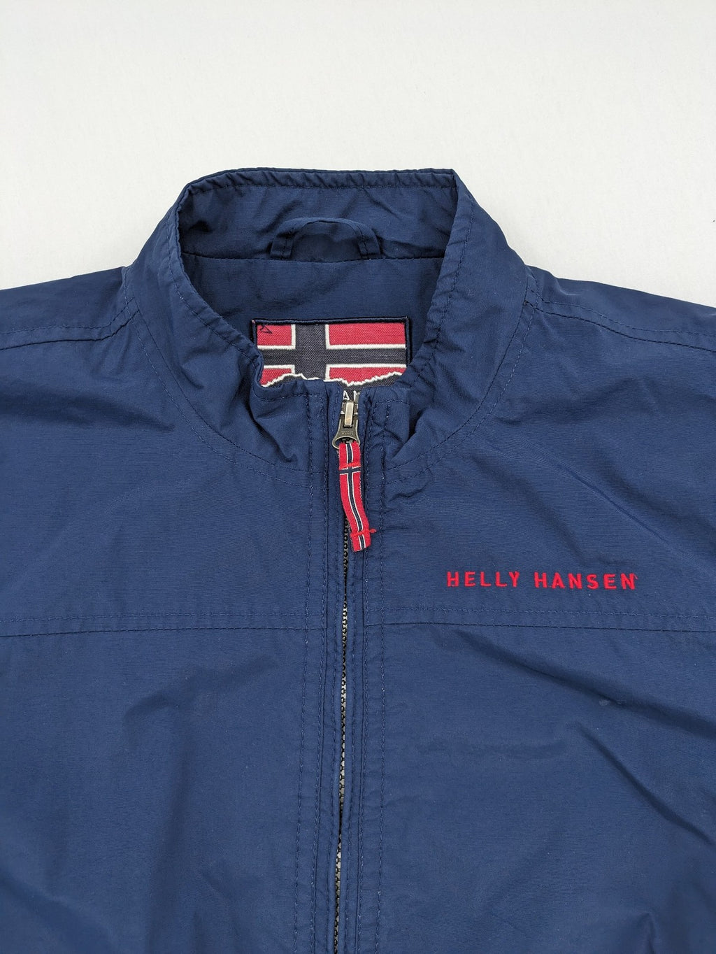 Helly Hansen navy jacket with red accents and logo, full zip, breathable mesh lining.