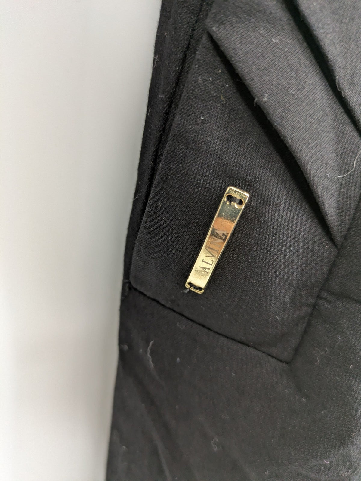 Alvina black trench coat with lace collar and gold buttons, belted waist design.