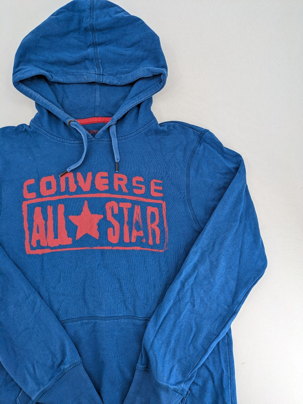 Converse All Star blue zip-through hoodie with red graphic logo and kangaroo pocket.