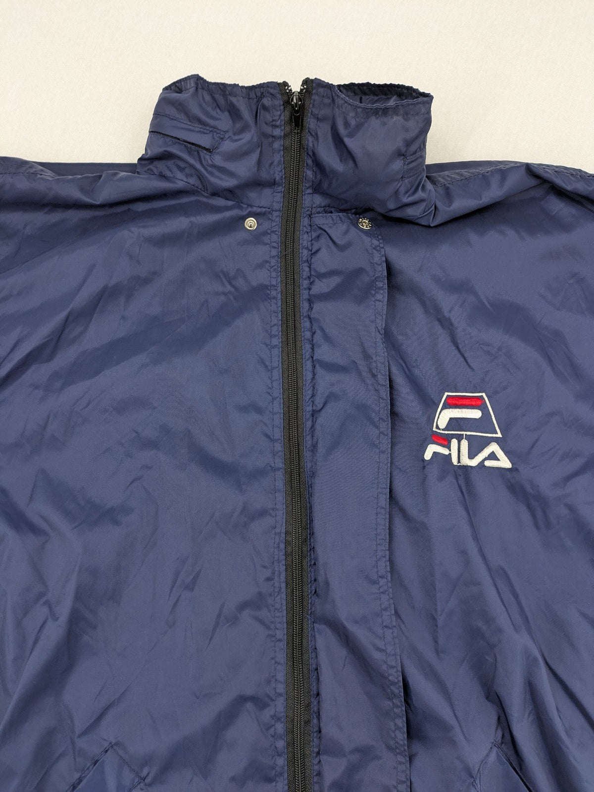 Fila navy windbreaker jacket with large embroidered logo on chest and back.