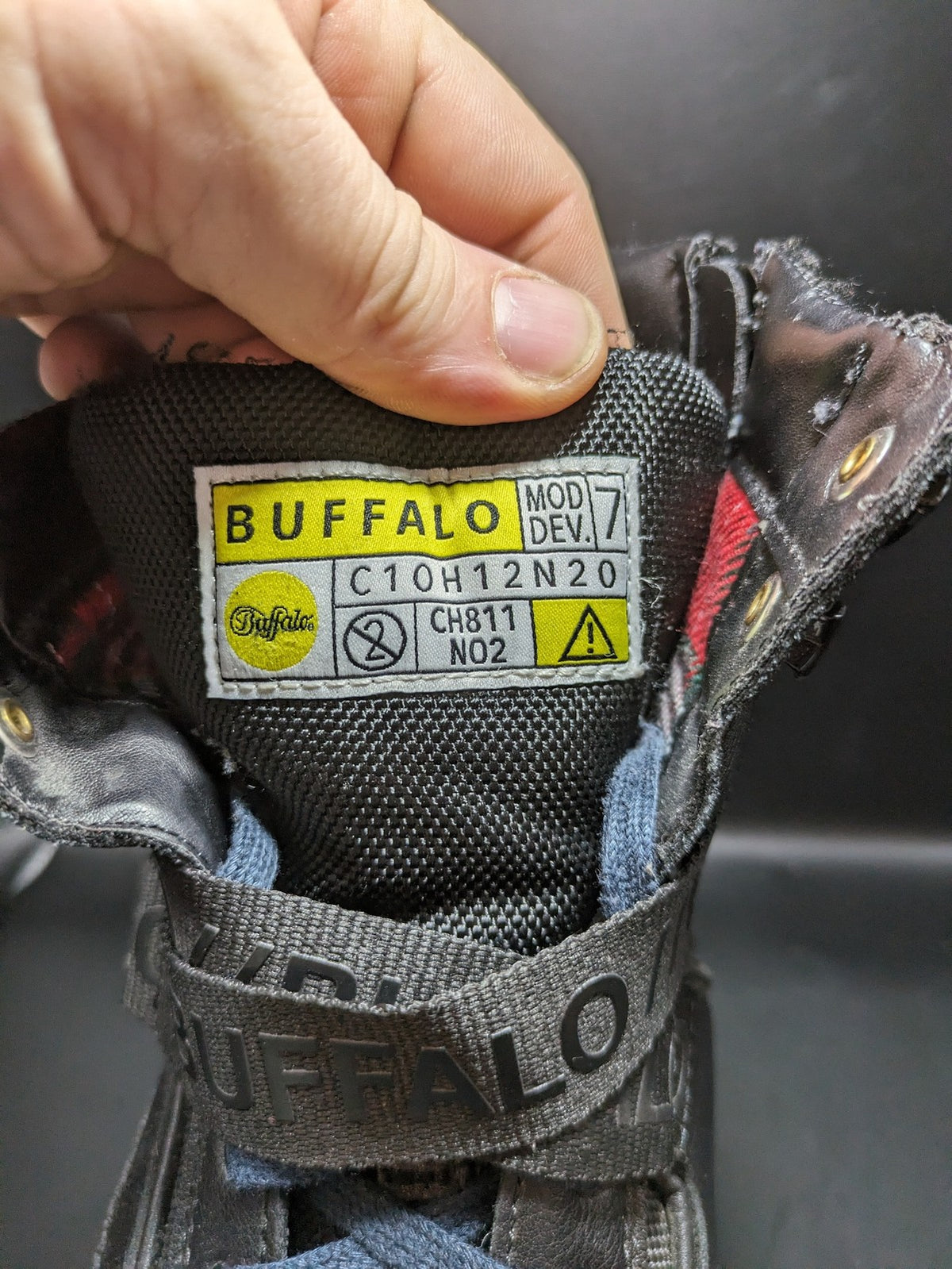 Buffalo black motorcycle boots with chunky sole, adjustable buckle strap, and red plaid lining.