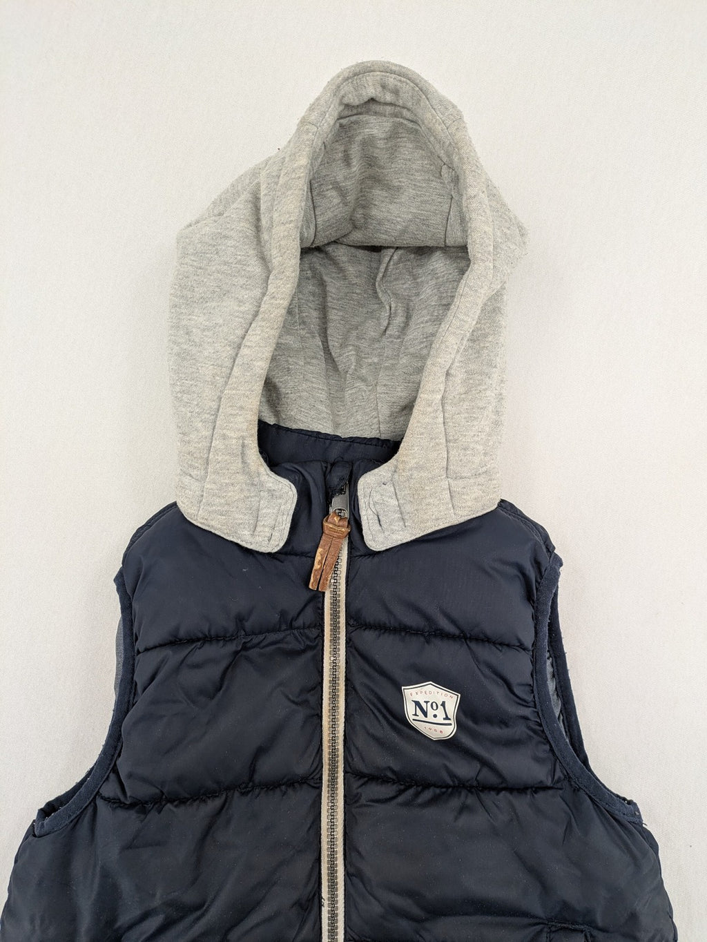 H&M navy puffer vest with grey hood and zip pockets for kids.