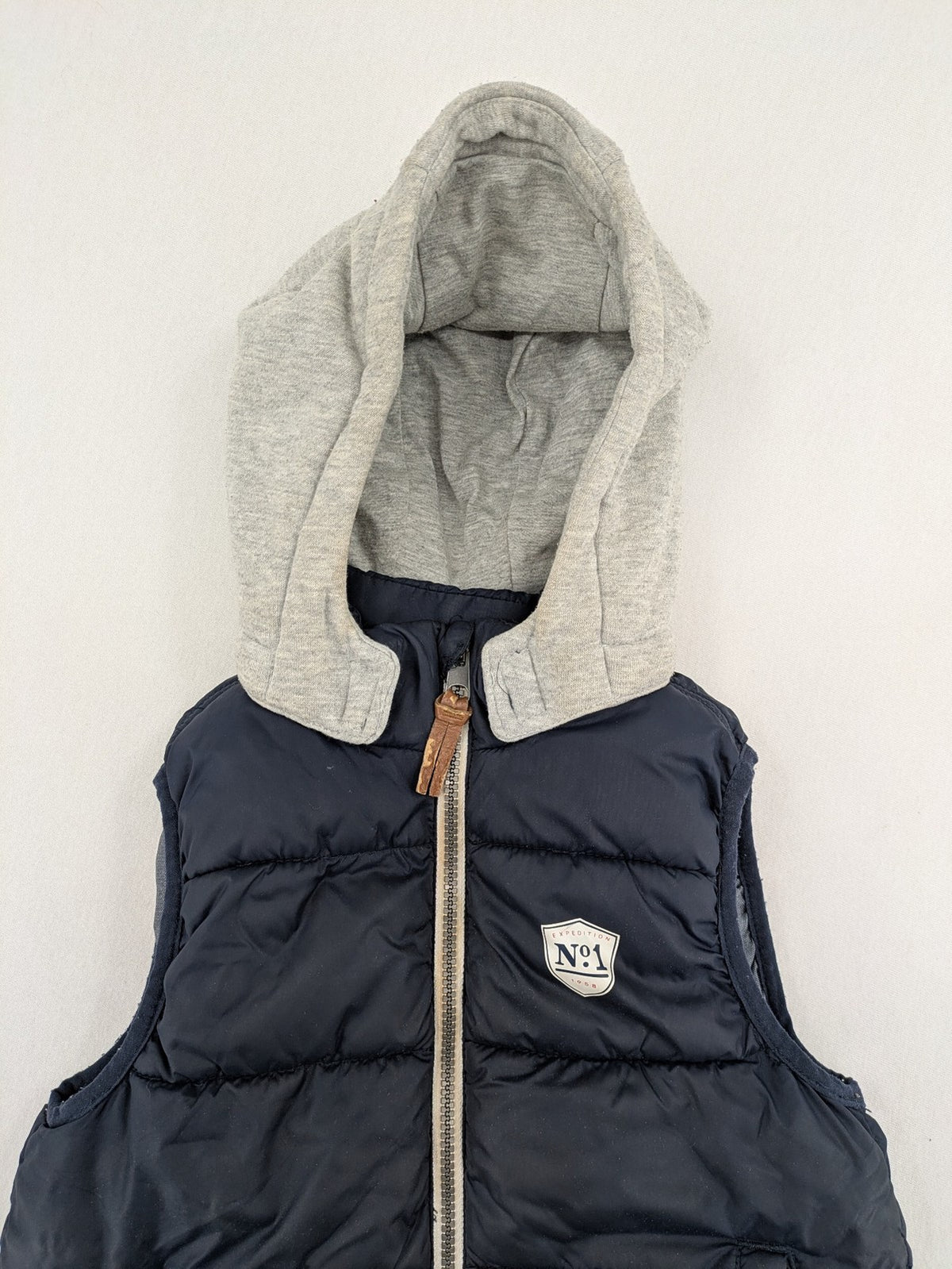 H&M navy puffer vest with grey hood and zip pockets for kids.