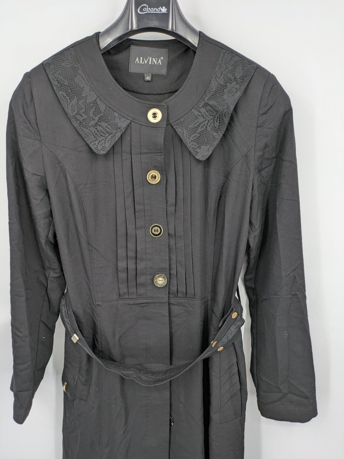 Alvina black trench coat with lace collar and gold buttons, belted waist design.