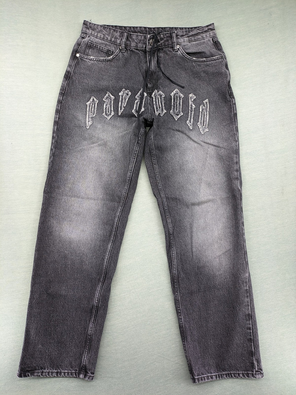 Black Squad black straight jeans with Gothic "Paranoid" lettering and faded finish.