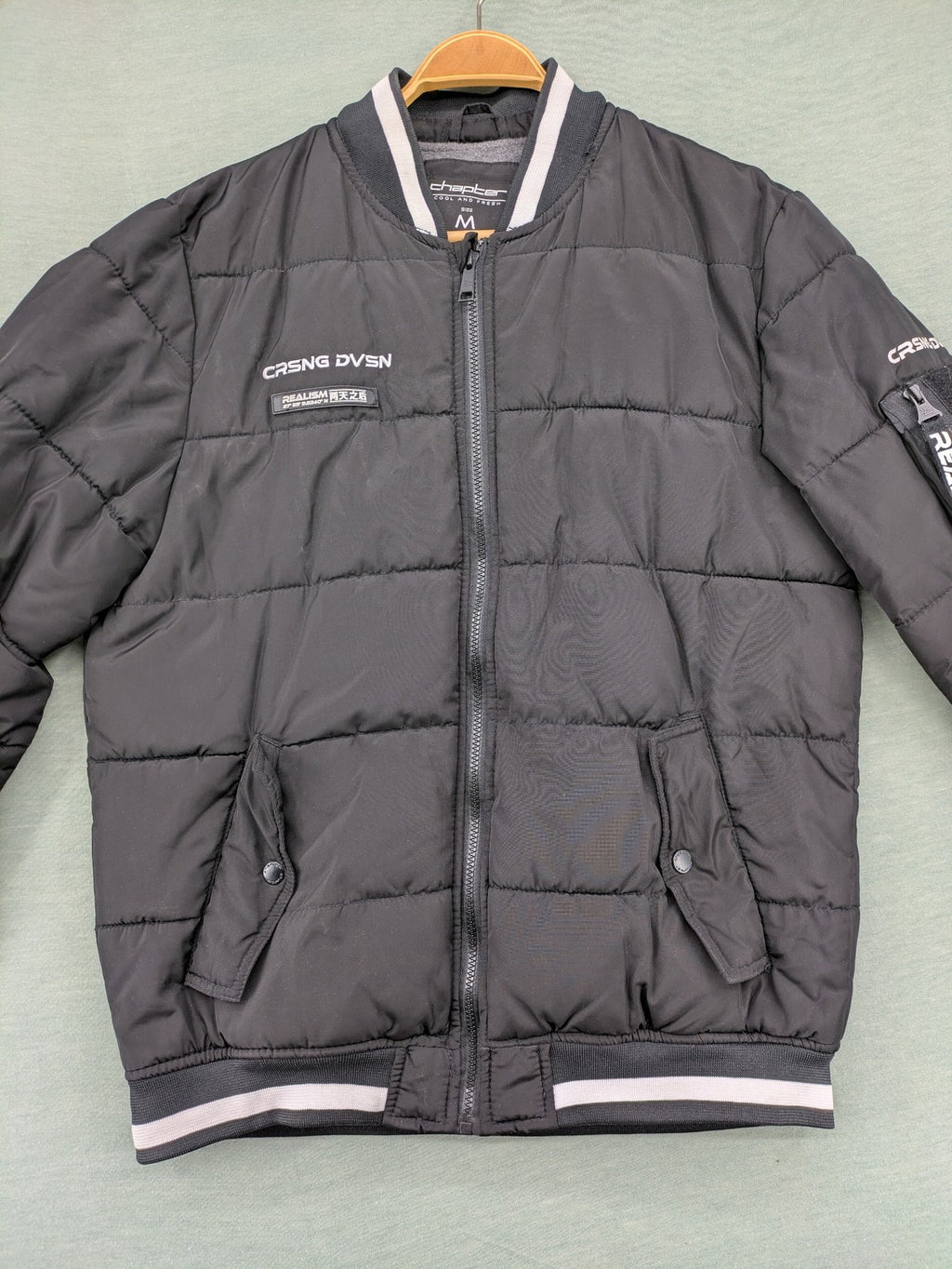 Chapter black bomber jacket with patches, striped ribbed cuffs, and full zip closure.