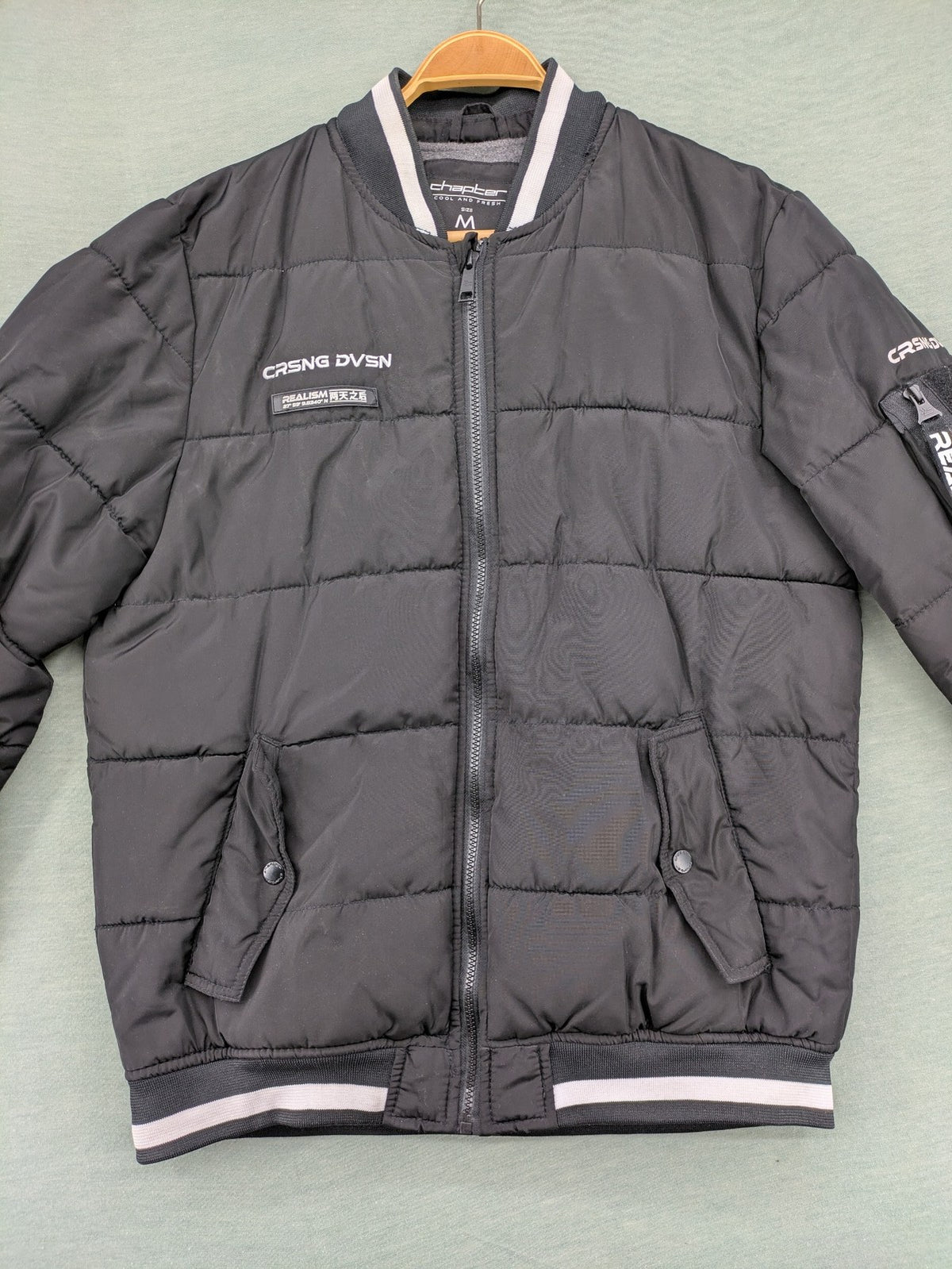 Chapter black bomber jacket with patches, striped ribbed cuffs, and full zip closure.