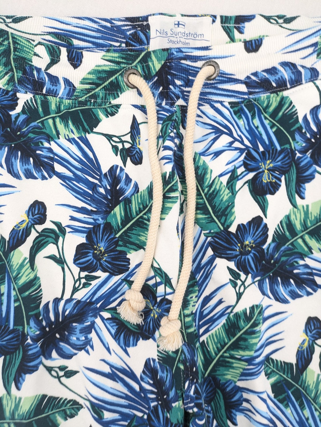 Nils Sundström blue and green tropical floral shorts with white background and elastic waistband.